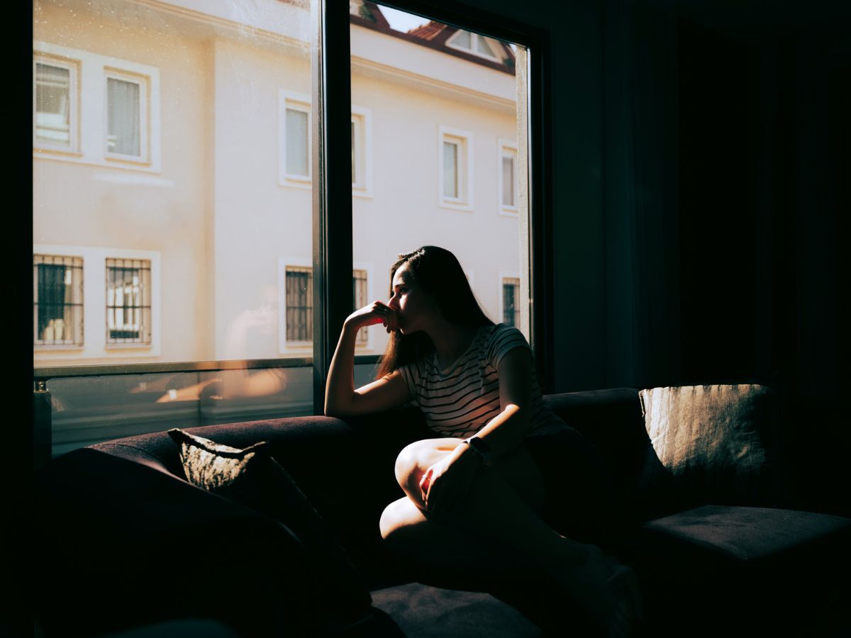 szomorú nő sötét szobában otthon depressziós