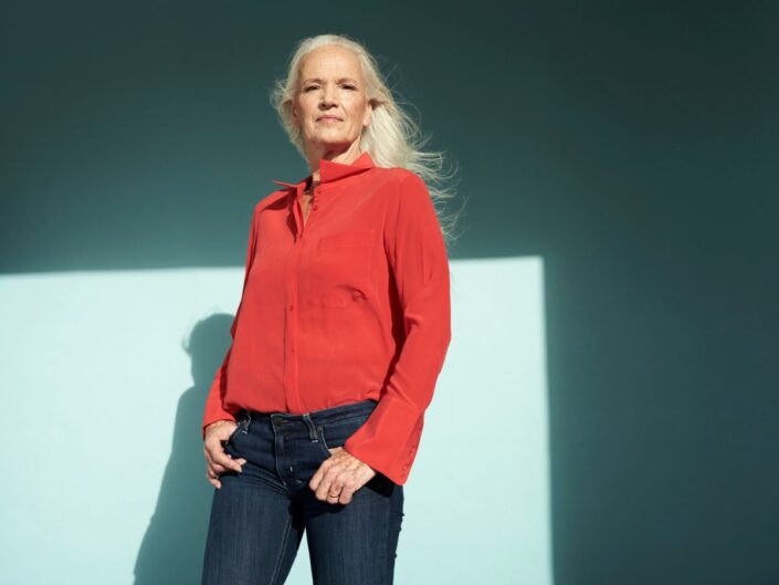 idősebb ősz hajú nő piros ingben áll