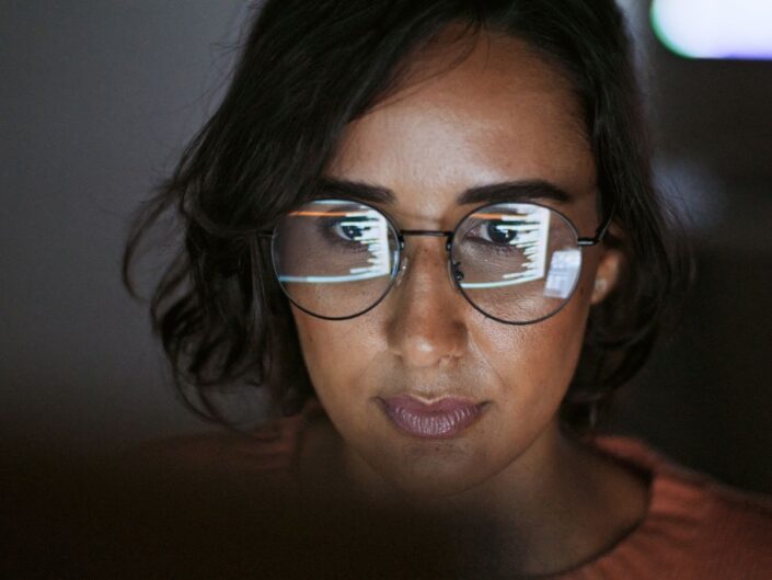 fiatal nő szemüveges számítógép előtt sötétben dolgozik