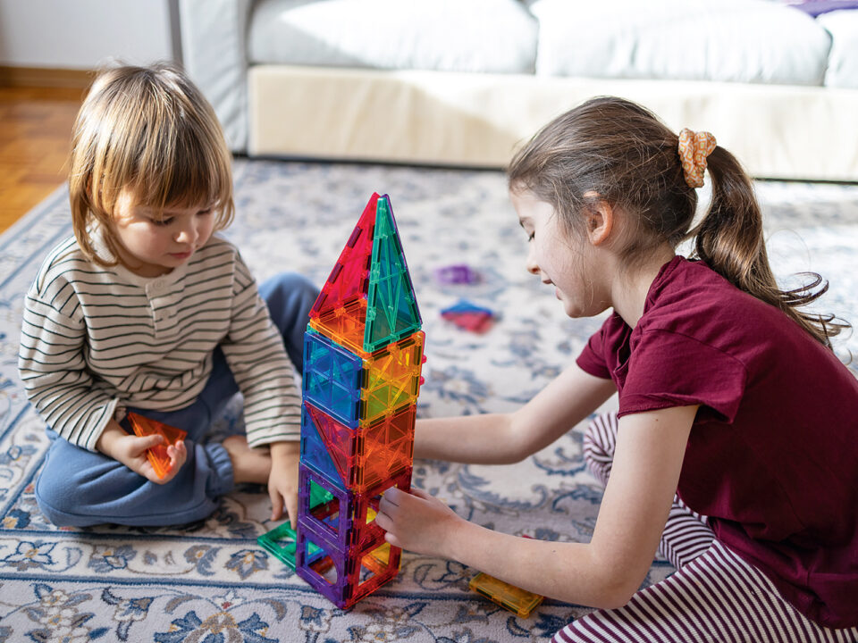Little children playing with magnetic blocks on the floor at home - Nők Lapja
