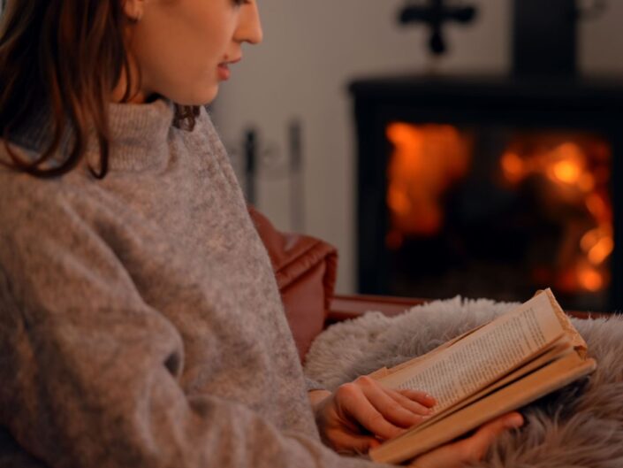 fiatal nő otthon kályha olvas ősz pulóver könyv