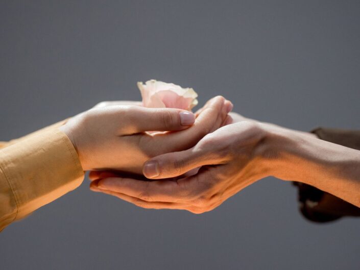két kéz egymáson virágot tart