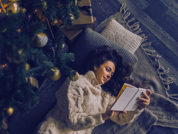 karácsonyfa alatt olvasó nő könyv