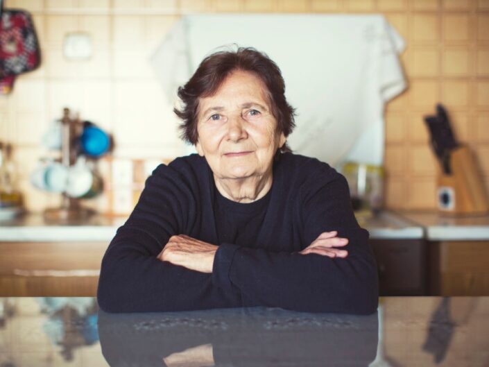 idős nő otthon asztal ül