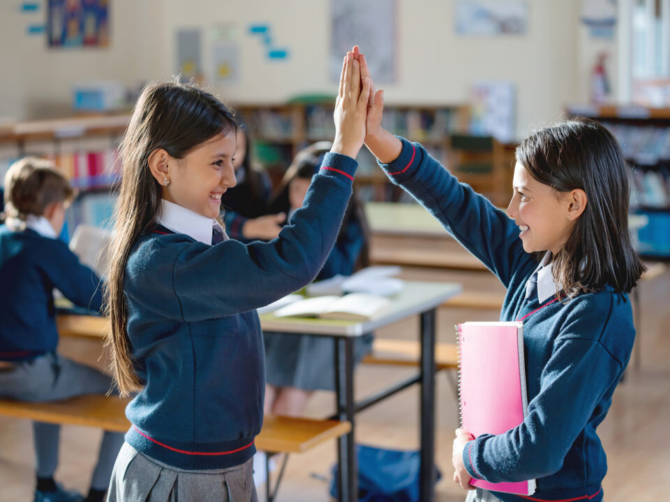 Happy students amaking a giving a high-five at the school - Nők Lapja