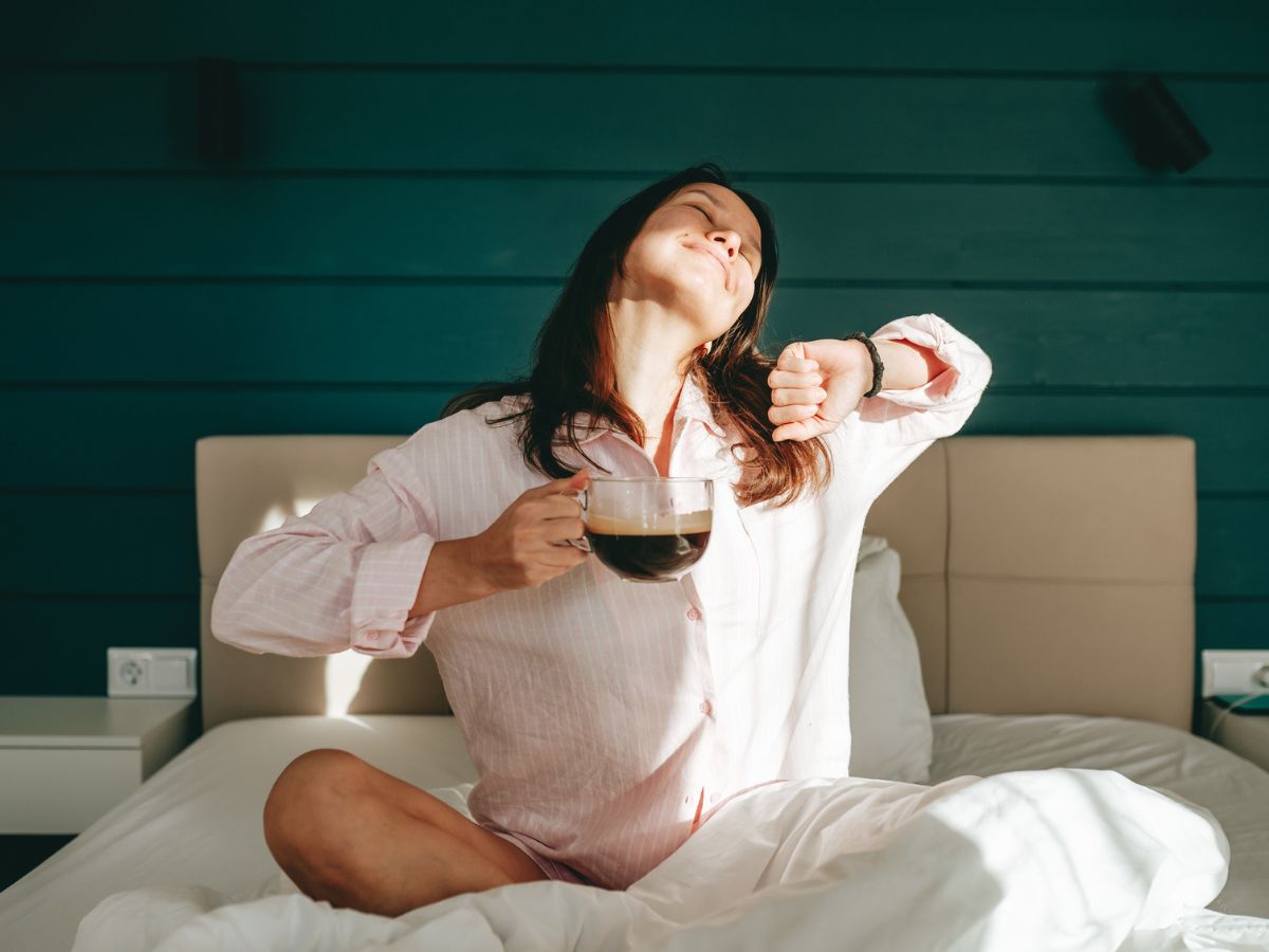 fiatal nő otthon ágy pizsama kávé napsütés reggel