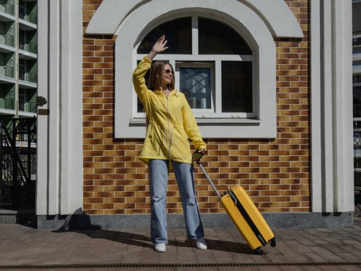 otthonról elköltöző fiatal nő sárga bőrönddel
