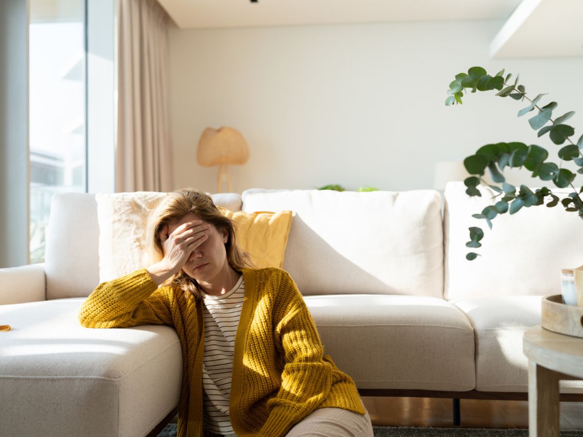 szomorú nő otthon kanapé arcát takarja