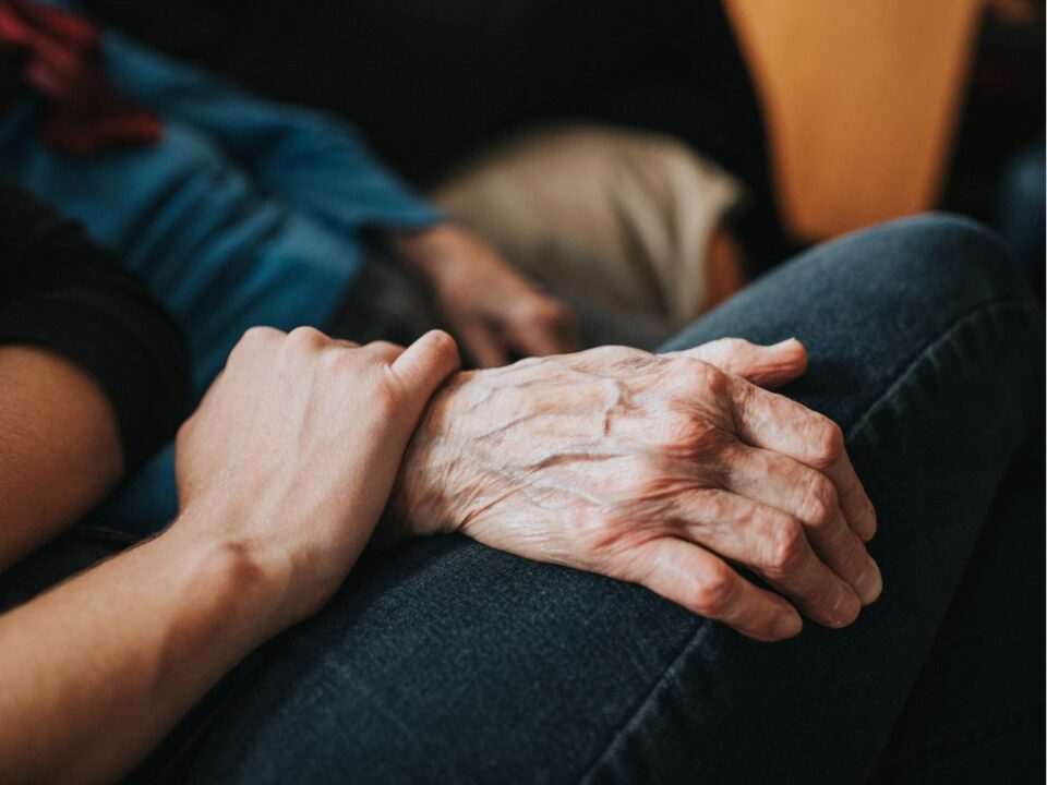 repulesre-keszen-racz-zsuzsa - Nők Lapja idős nő kezét fogja az egyik családtagja