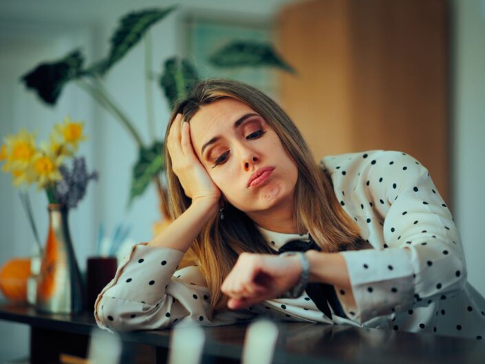 fiatal nő asztal könyököl óráját nézi fejét támasztja