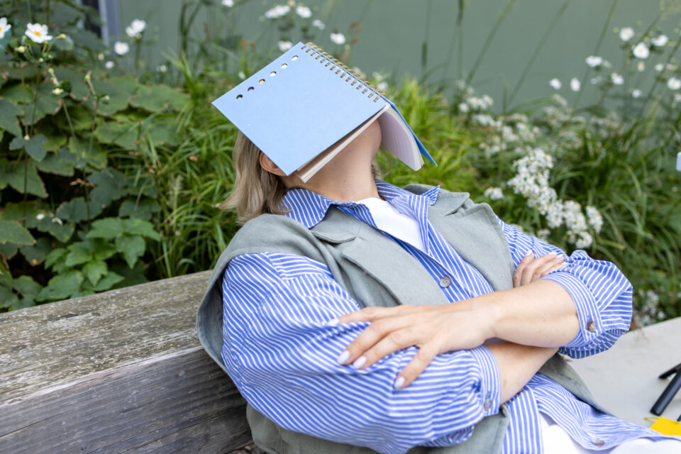 Tired female student taking a break outside head covered with book Post secondary education - Nők Lapja