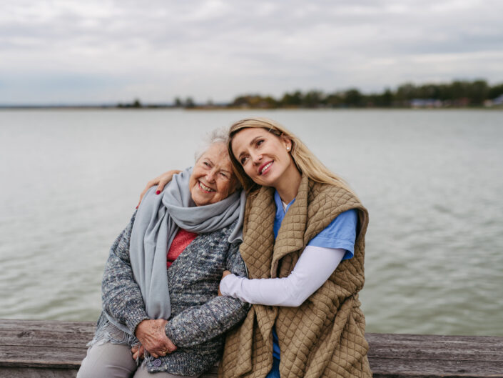 Idős nő és fiatalabb egy hűvös napon a szabadban, a tóparton ülnek , őszi séta