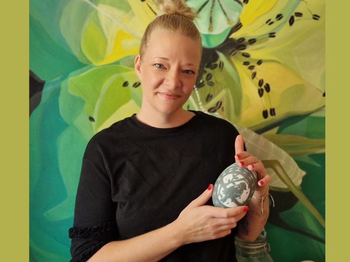 Tóth-Kiss Hajnalka pedagógus virágos fal előtt