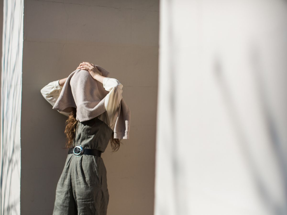 Fiatal nő eltakarja az arcát a pulóverével