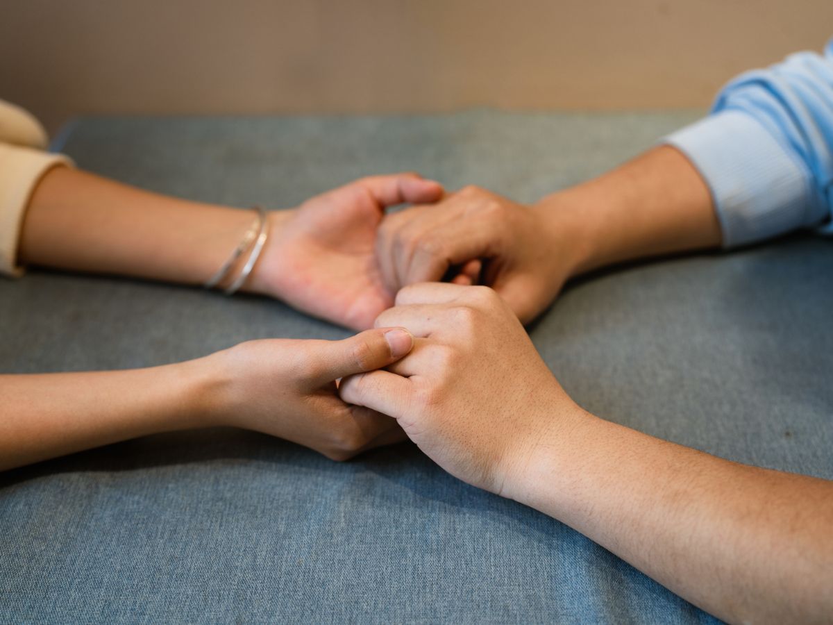 Két személy gyengéden fogja egymás kezét