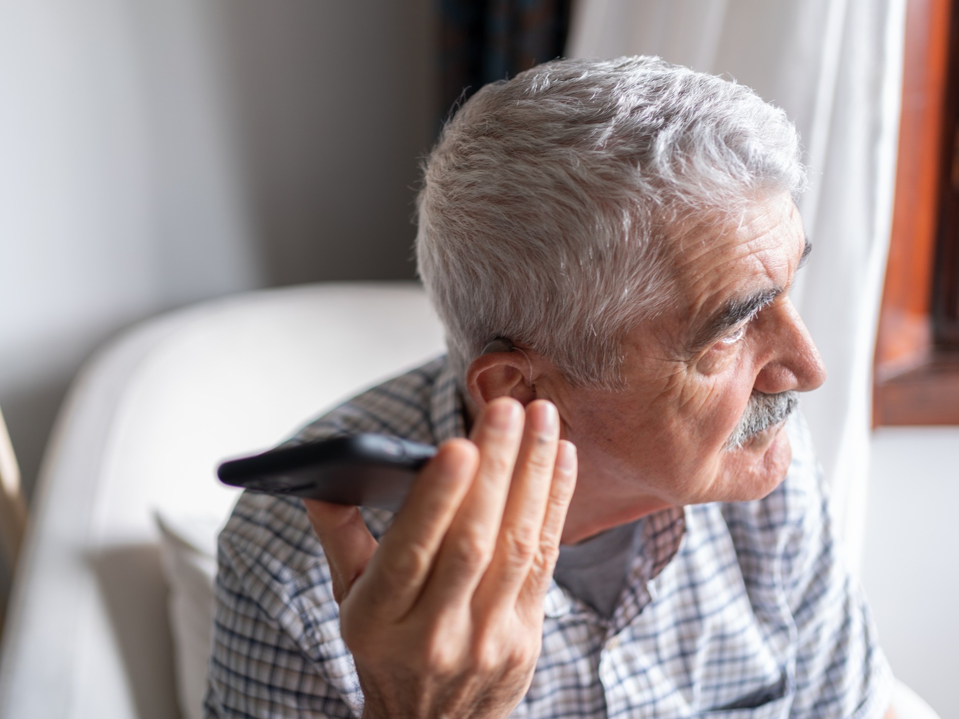 idős ember a füléhez tartja a telefonját