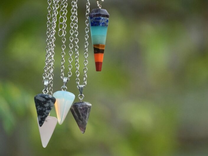 láncon lógó kúp alakú ásványok zöld háttér előtt