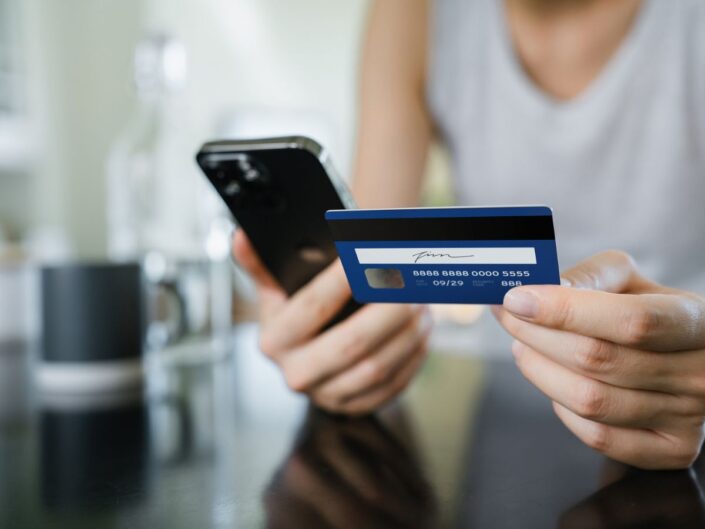 nő telefonnal és hitelkártyával a kezében