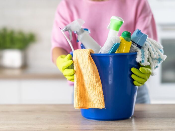 egy nő tisztítószereket tart a kezében