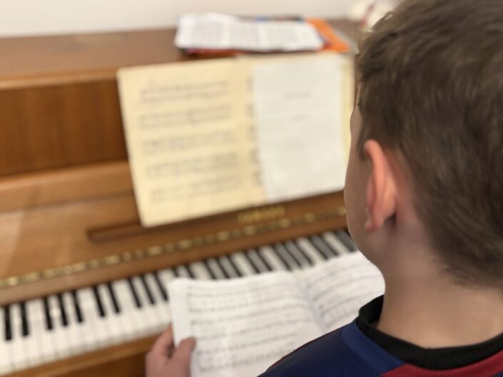 kisfiú kottával, zongorával