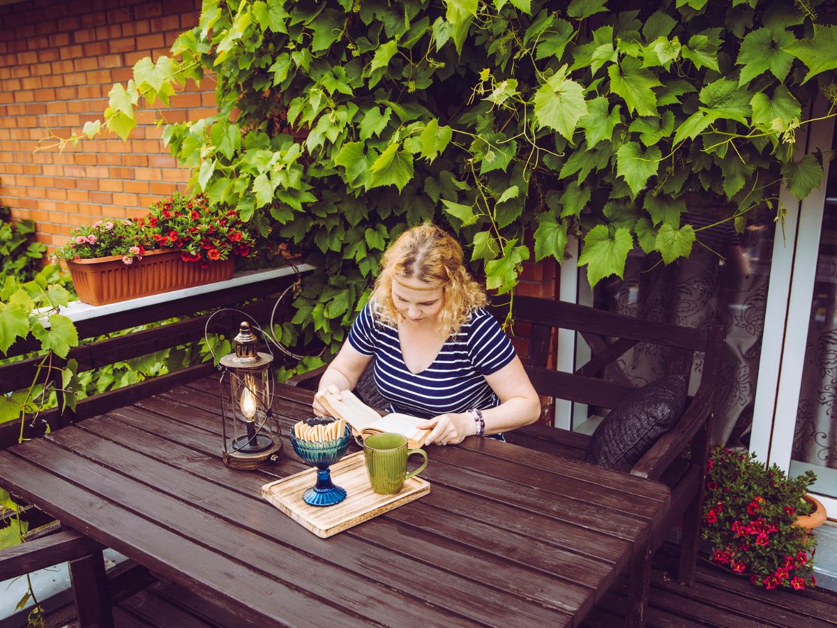 fiatal nő könyvet olvas az erkélyen