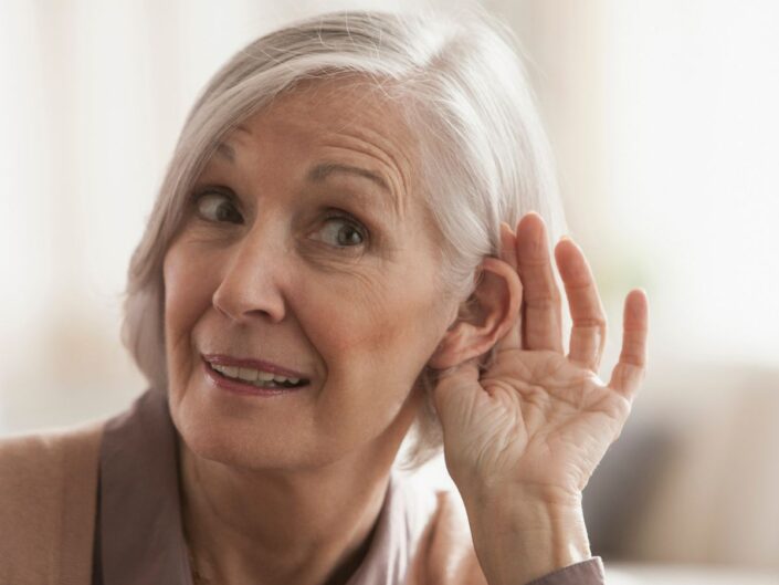 idősödő nő tölcsért formál a kezével a füléhez