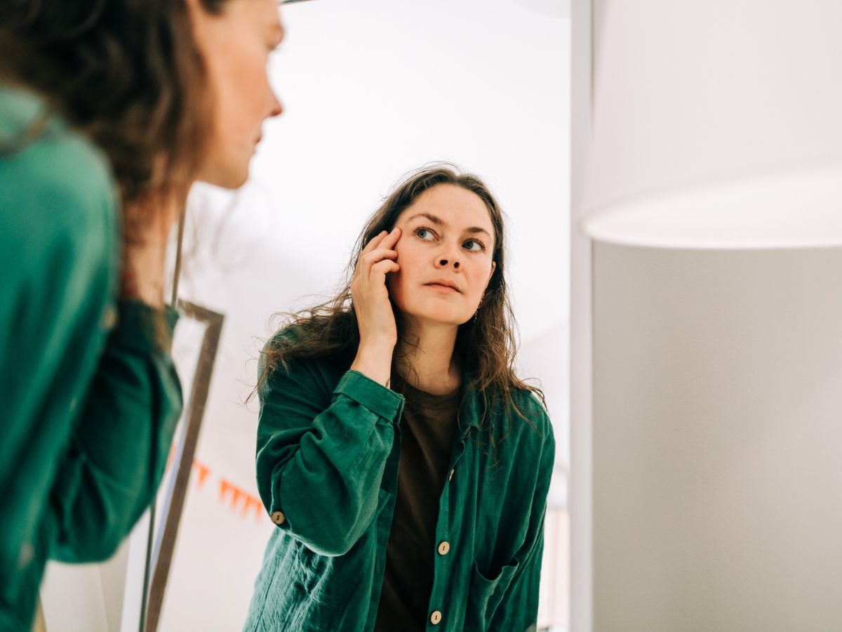 középkorú nő a tükörben nézi magát