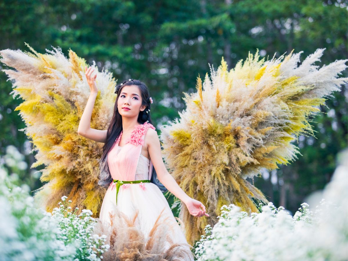 Angyalszárnyakat viselő fiatal nő tavasszal