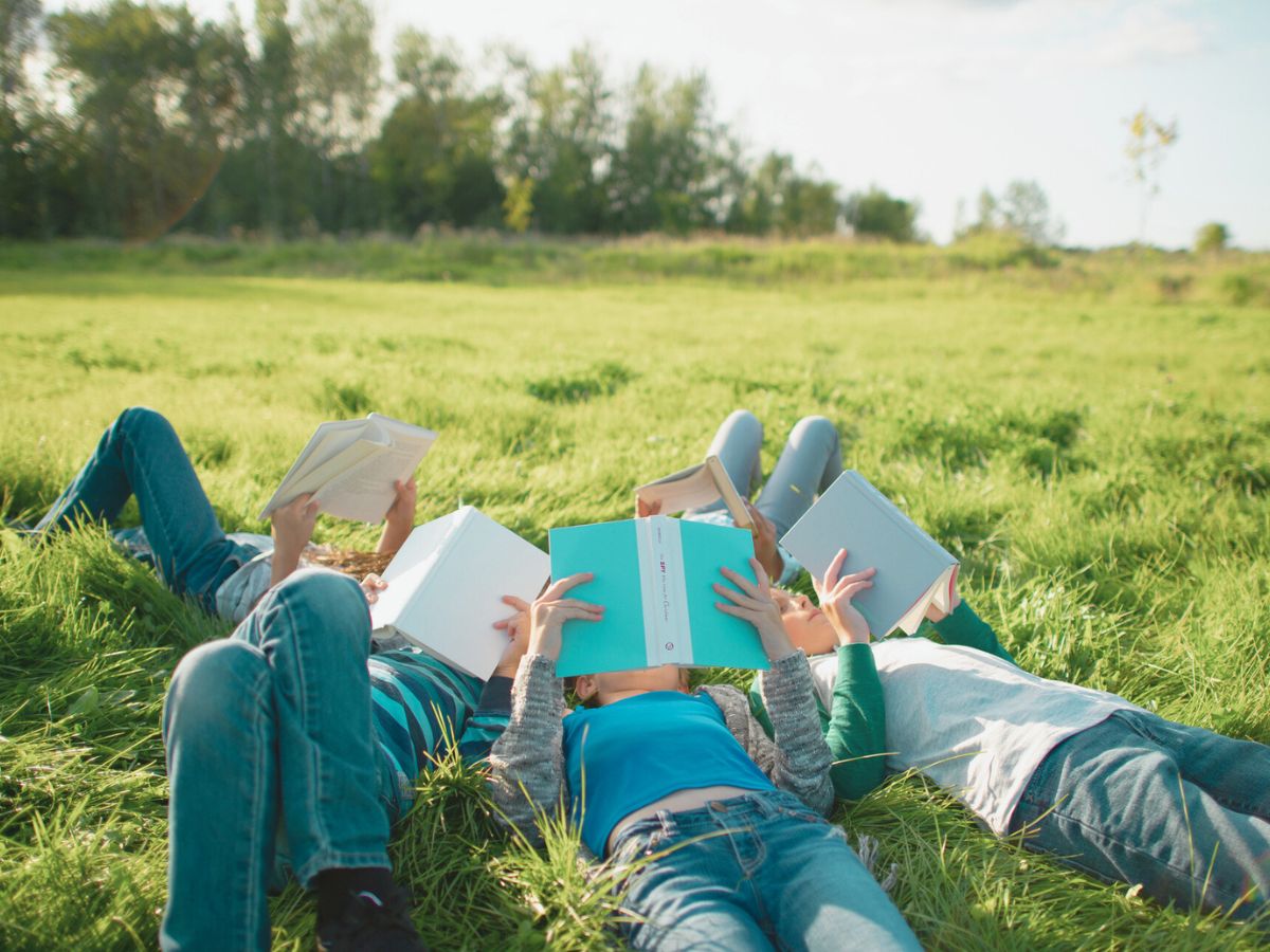 gyerekek olvasnak könyveket a mezőn a fűben fekve