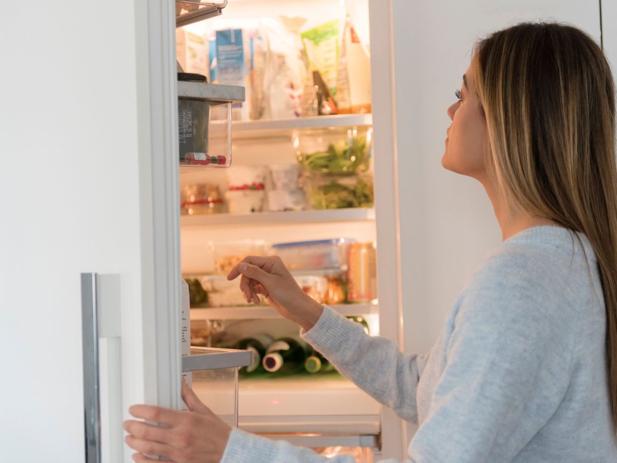 nő áll nyitott hűtőszekrény előtt