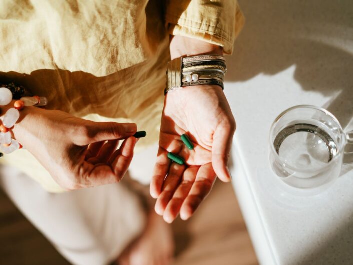 zöld színű kapszulák egy nő kezében