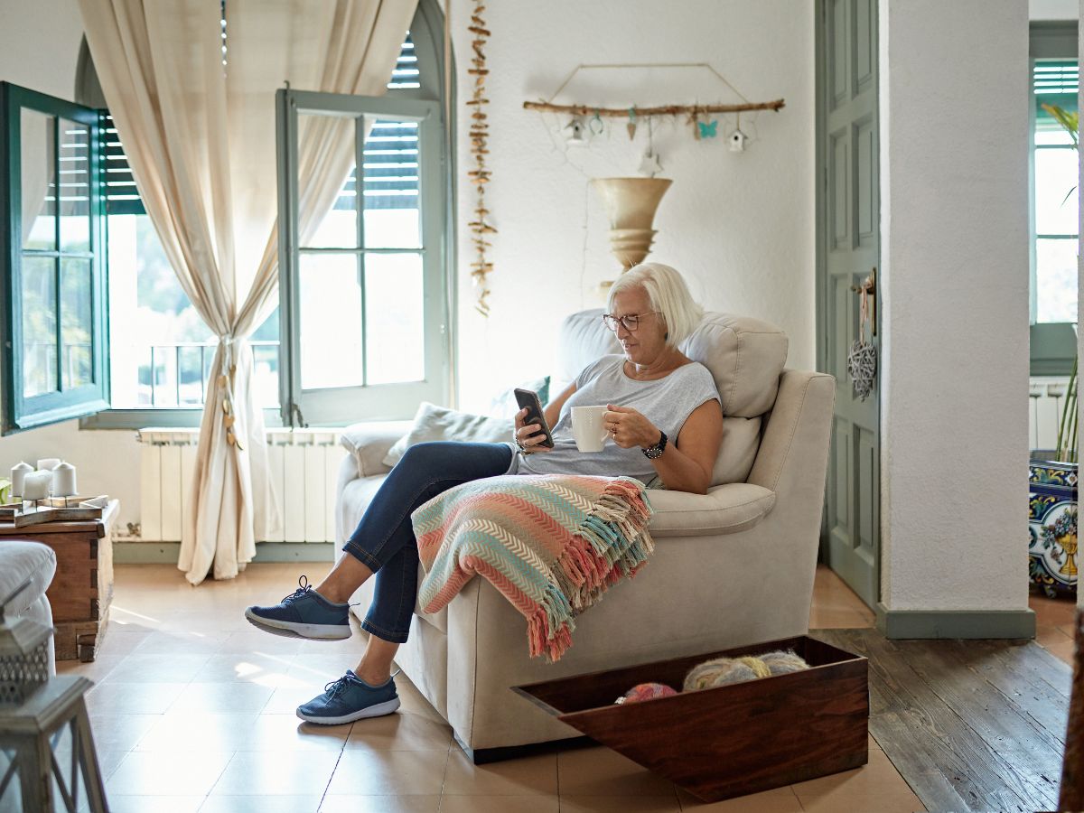 ötvenes nő kávézik a nappali foteljában