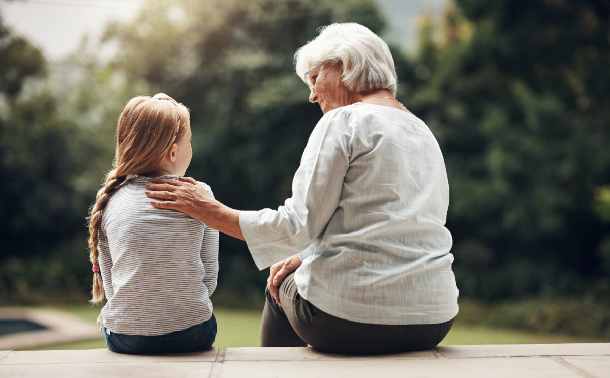 nagymama és unokája háttal ül a terasz lépcsőjén és egymásra néznek