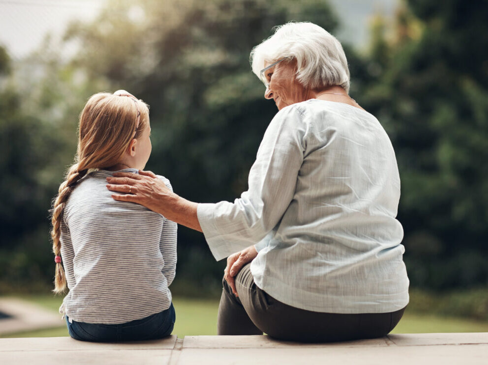 nagymama és unokája háttal ül a terasz lépcsőjén és egymásra néznek