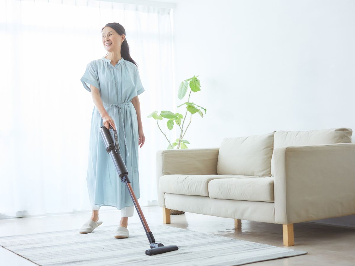 vidám, fiatal nő porszívózik