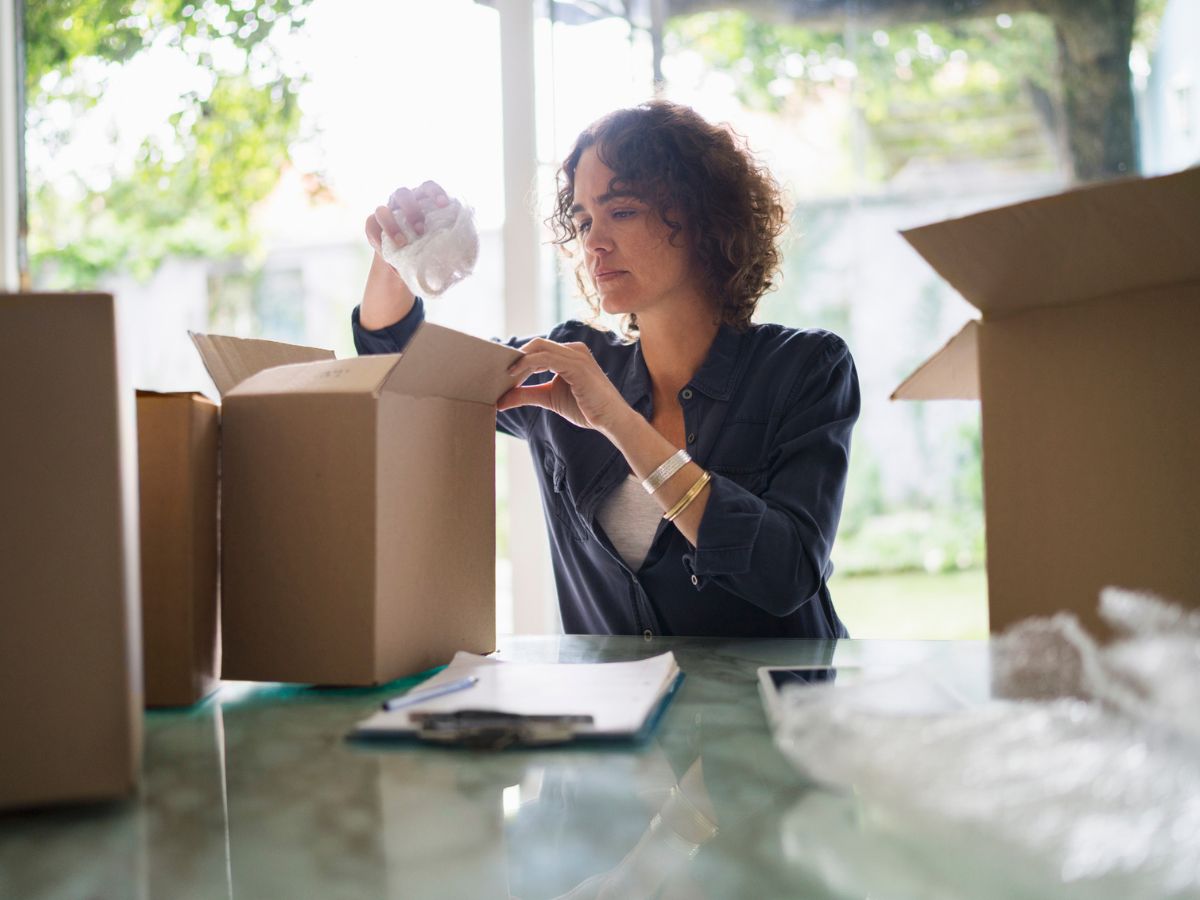 fiatal nő az asztalra tett kartondobozból pakol ki