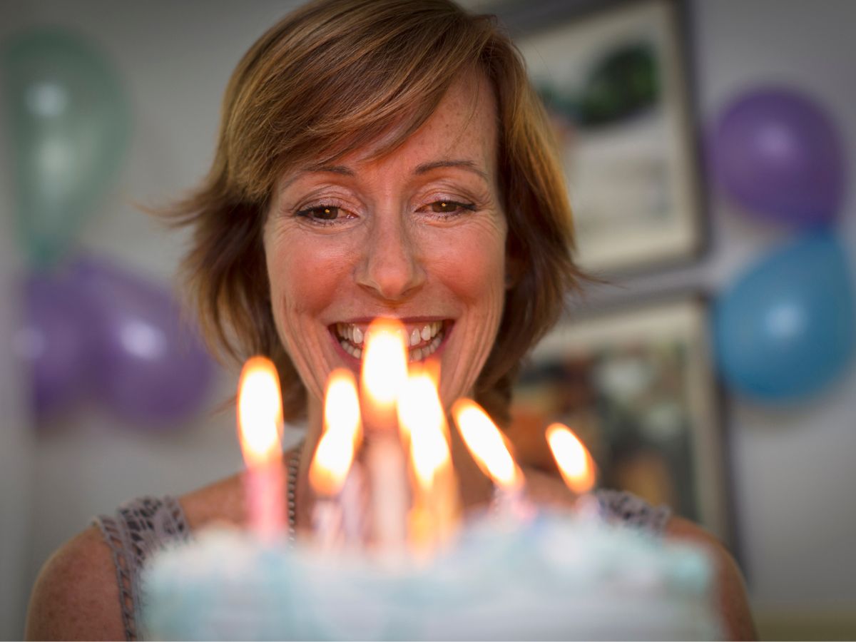 nő boldogan nézi a szülinapi tortáját