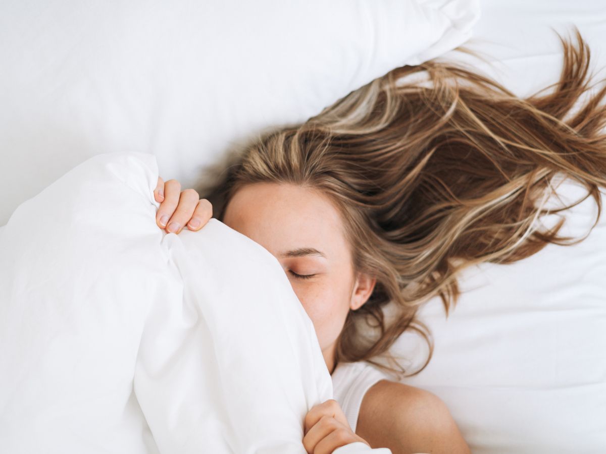 fiatal nő fehér paplan alatt alszik