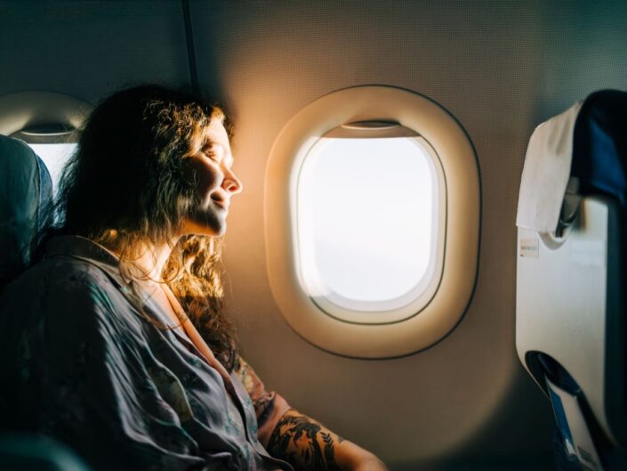 repülőn utazó nő élvezi az ablakon bejövő napfényt