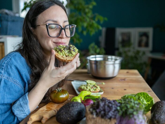 szemüveges nő avokádókrémes kenyeret eszik