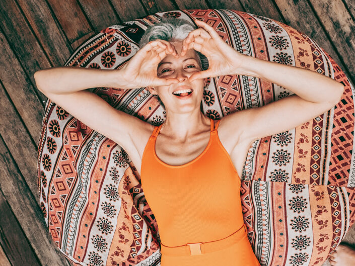 nő párnán fekszik szívet mutat a kezével