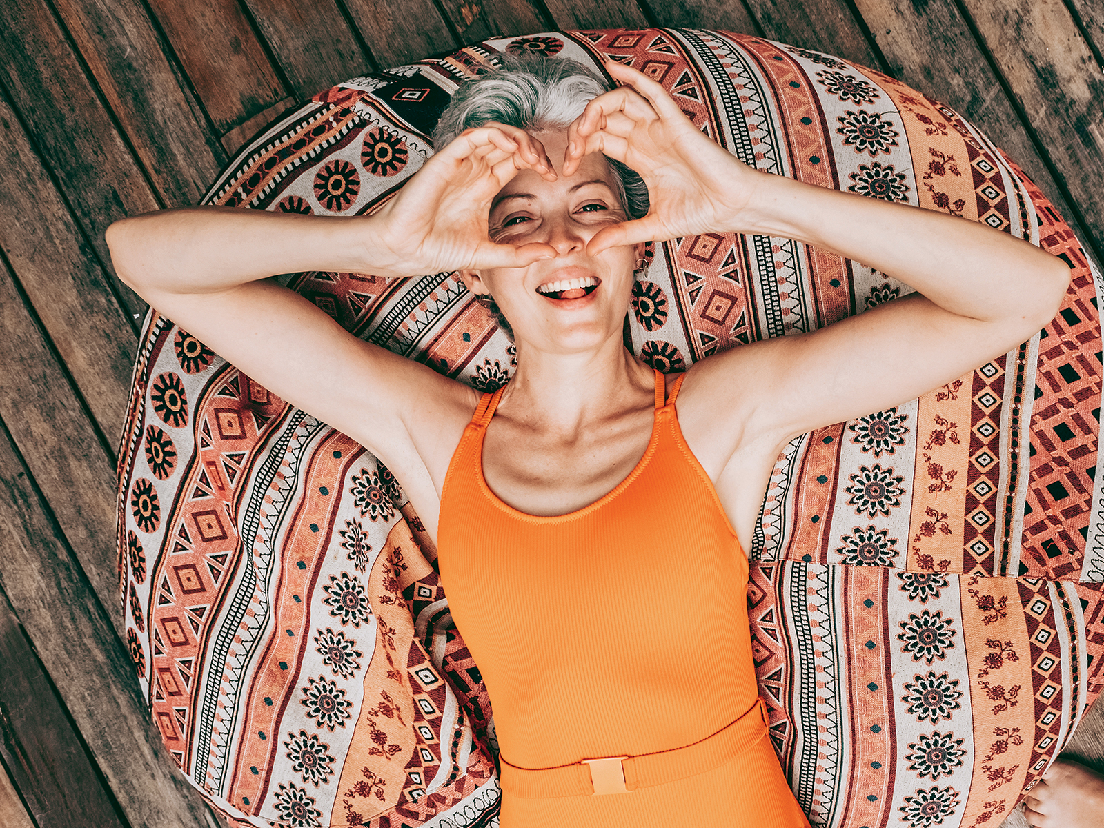 nő párnán fekszik szívet mutat a kezével