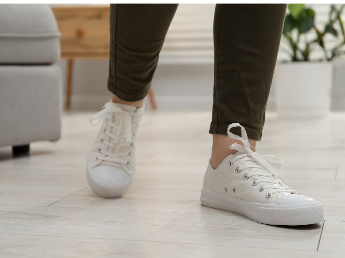 Nő lába fehér sportcipőben