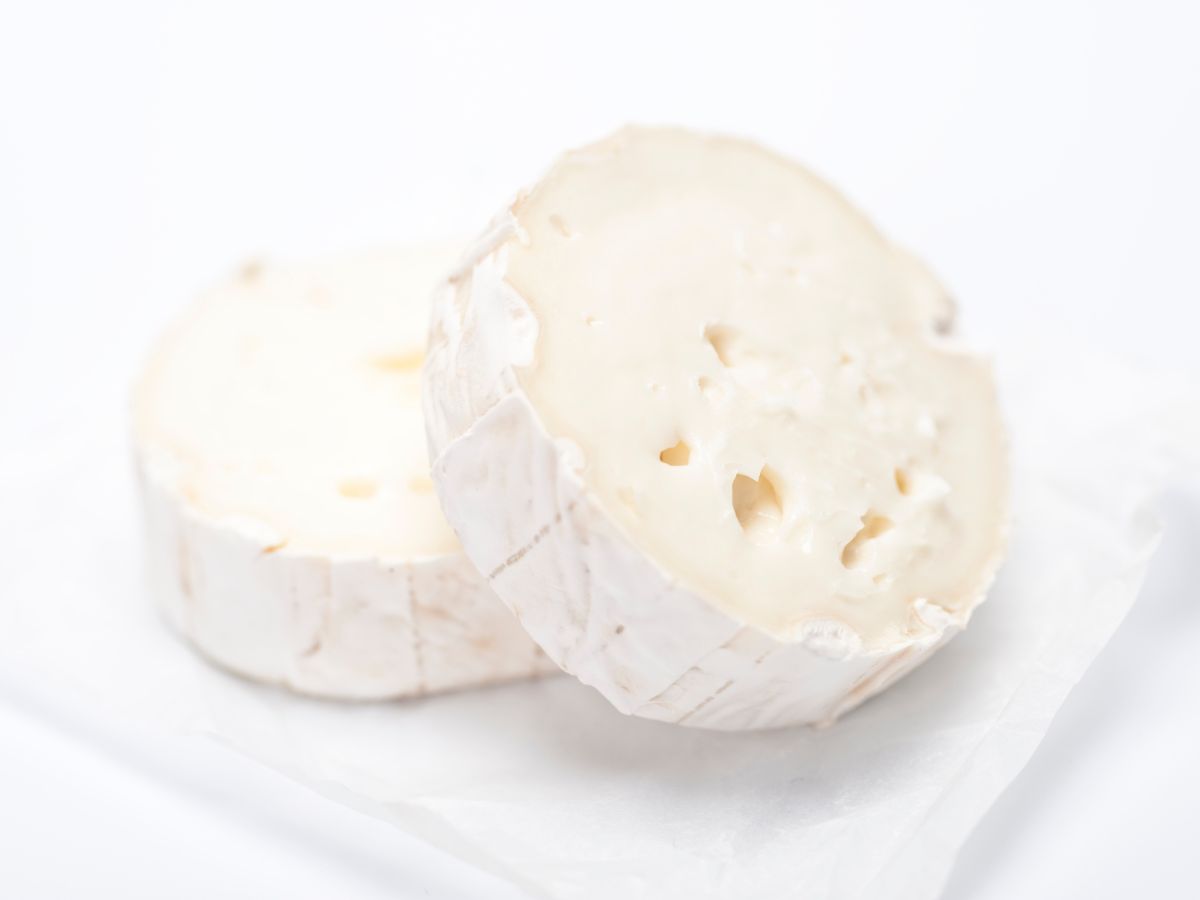 Két szelet kerek kecskesajt fehér háttéren