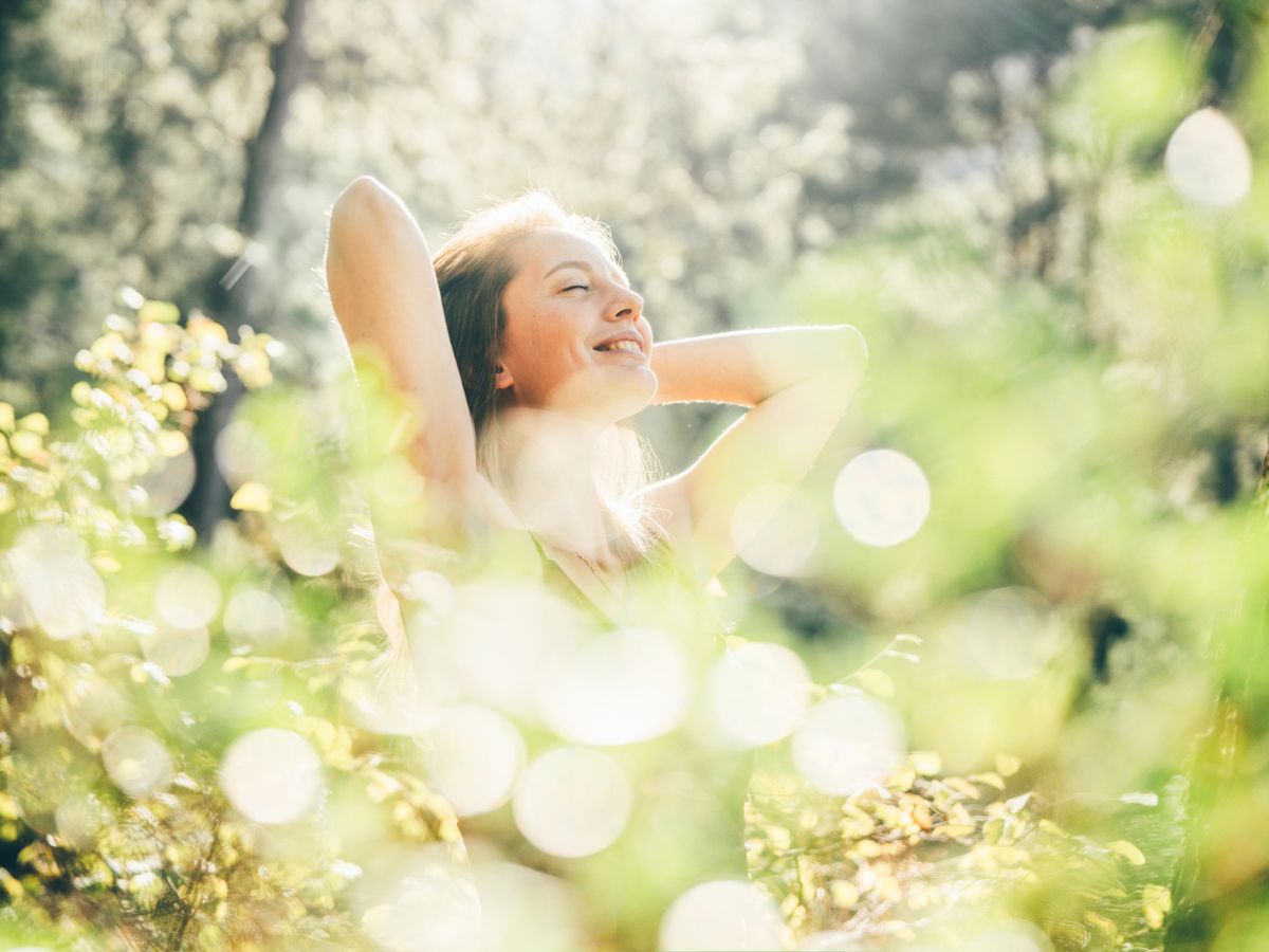 fiatal nő napsütésben, virágok között