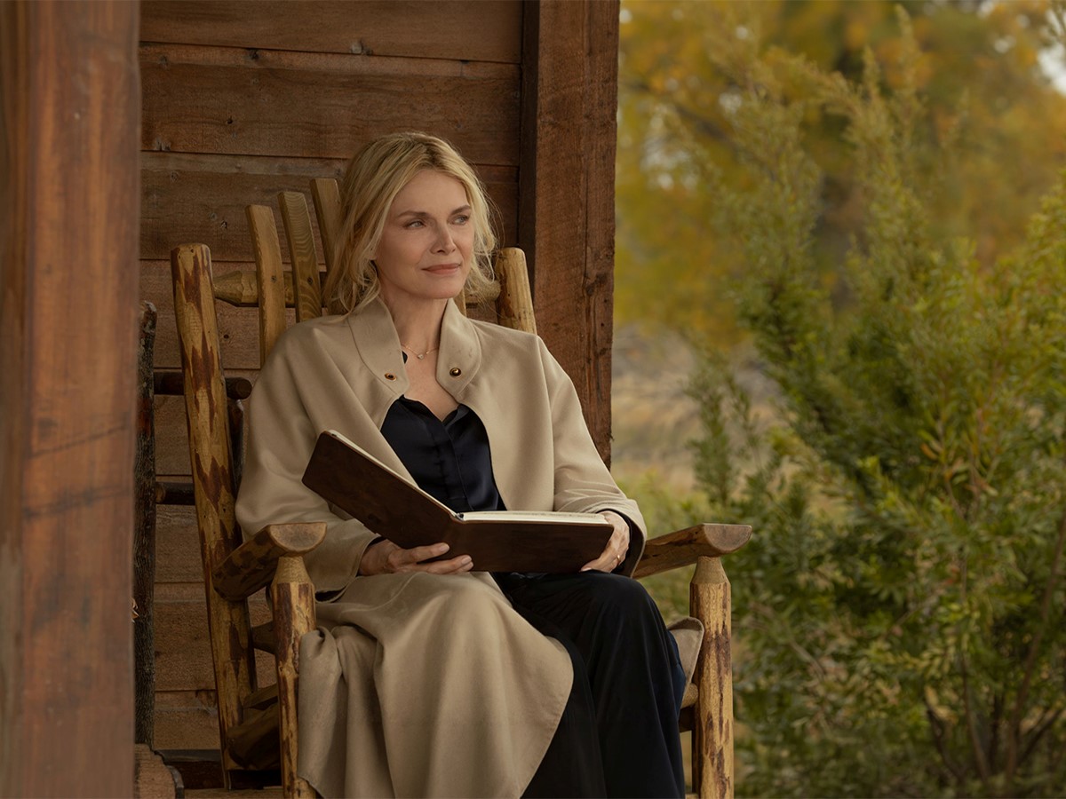 Michelle Pfeiffer a The Madison című sorozatban: hintaszékben ül egy faház verandáján, kezében nyitott könyv. Nyugodtan a távolba néz, körülötte zöld növények és őszi színek.