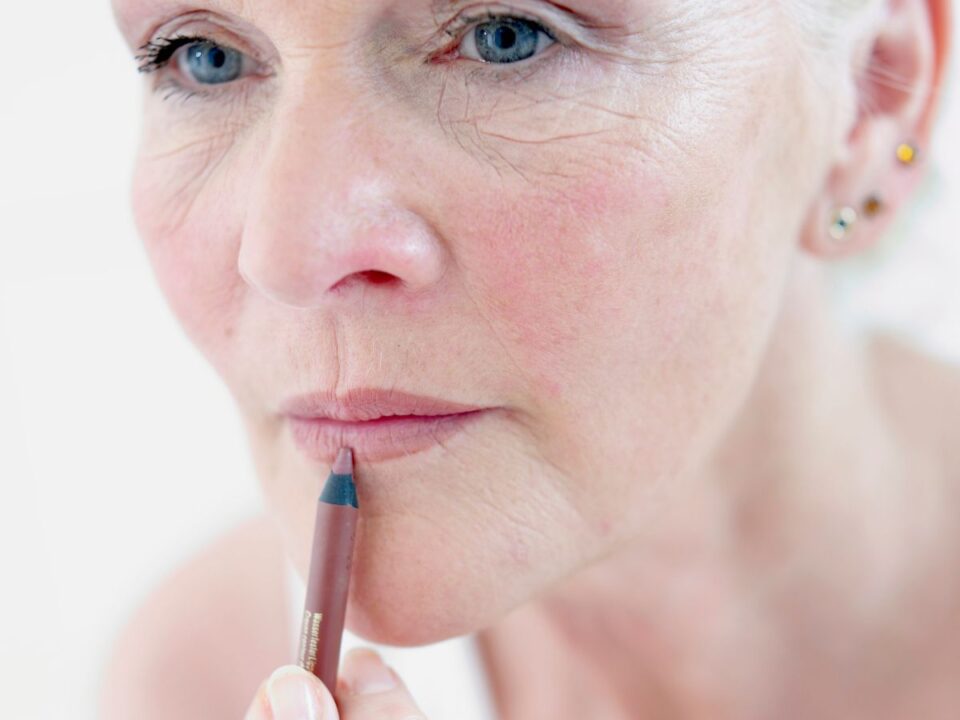 50 feletti nő ajakkontúrral satírozza a száját rúzsozás előtt közeli képen