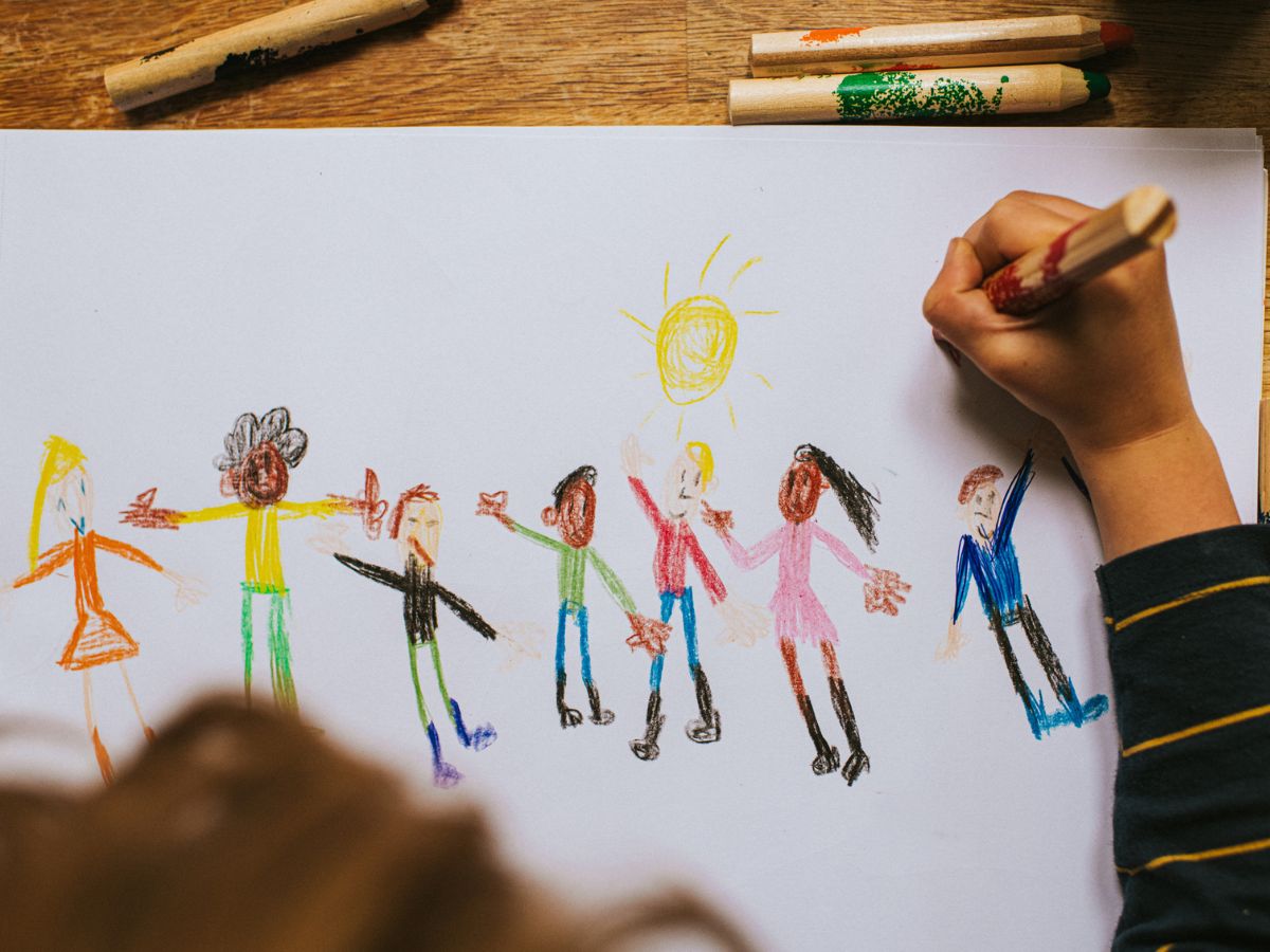 Egy kisgyerek különböző etnikumú embereket rajzol