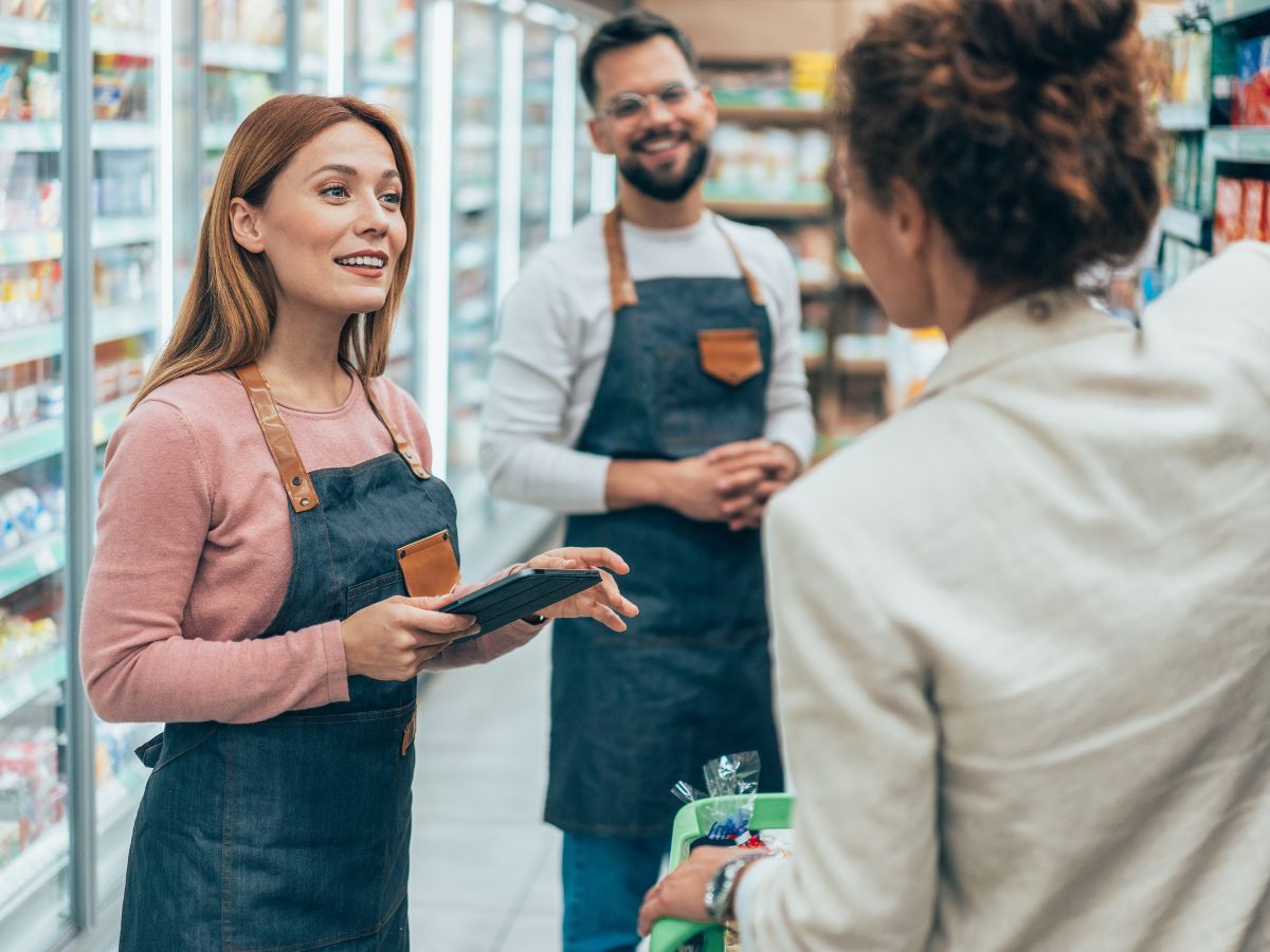Bolti eladók beszélnek háttal álló női vásárlóhoz