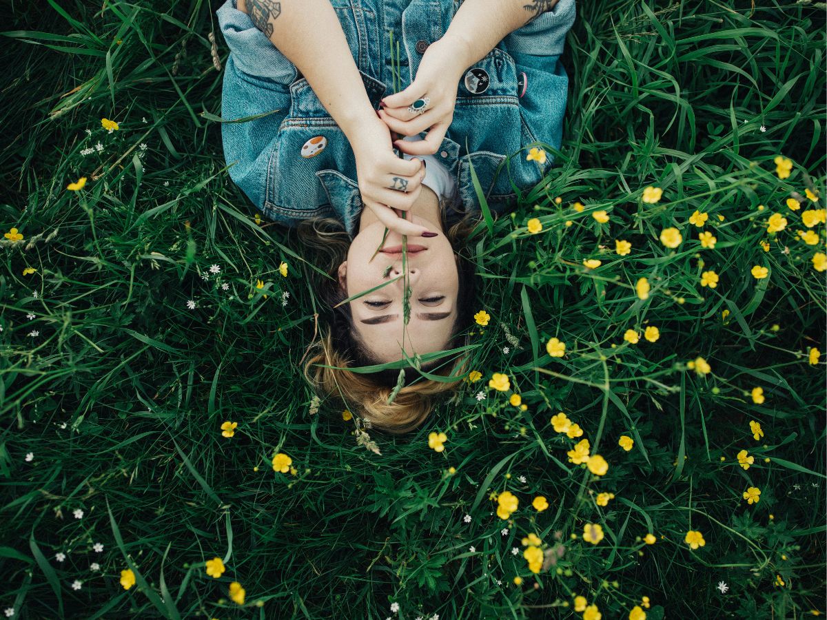 fiatal nő tavasszal a fűben, sárga virágok között